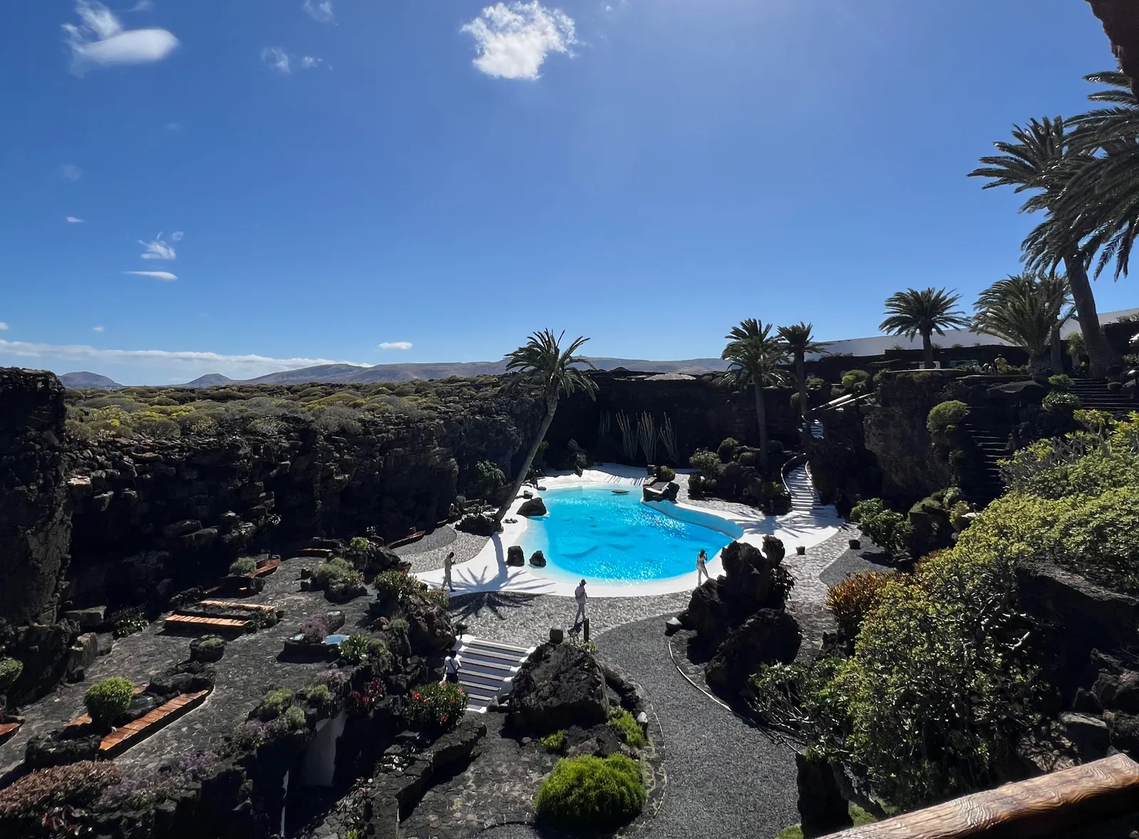 Outdoor turquoise pool of Jameos del Agua surrounded by palm trees and volcanic rock